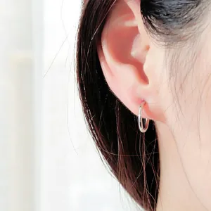 Close-up view of a minimalist silver stainless steel hoop ear clip worn on a model ear