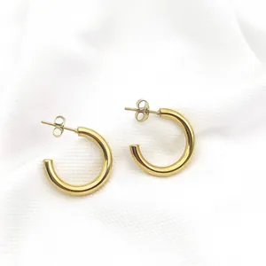 Elegant gold plated stainless steel C-shaped hoop earrings displayed on white textured fabric