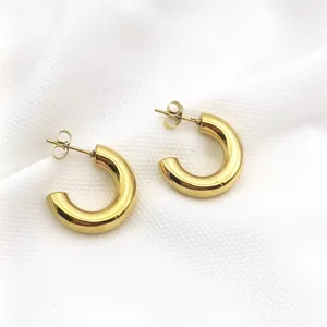 Macro detail of polished gold-plated stainless steel chunky C-shaped stud earrings