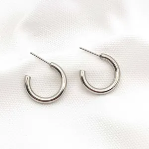 Close-up detail of minimalist silver stainless steel C-shaped hoop earrings for women