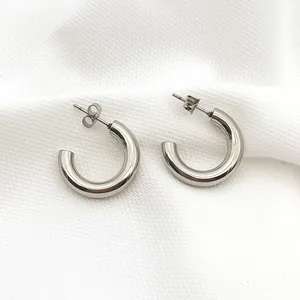 Detailed close-up of polished silver stainless steel C-shaped chunky hoop stud earrings