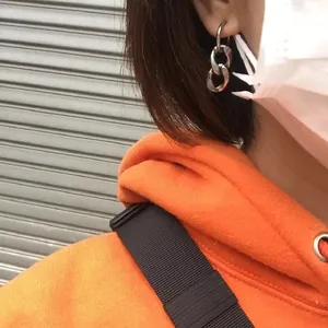Detailed view of fashionable stainless steel chain link earrings worn on the earlobe