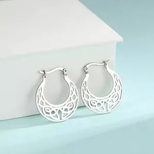 Close-up detail of silver hollowed crescent moon stainless steel hoop earrings on a box.