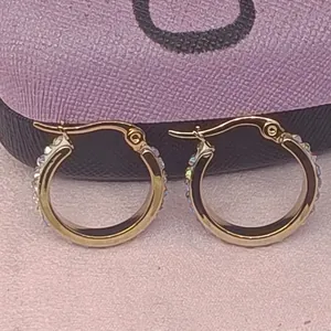 Detailansicht goldener Creolen aus Edelstahl mit mikrogefassten Zirkoniasteinen