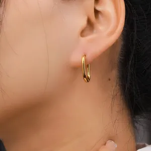 Close-up detail of minimalist oval 18k gold plated titanium steel earring worn on the earlobe