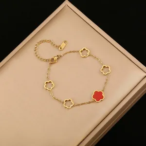 Primer plano de una pulsera de acero inoxidable dorada con flor roja de cinco pétalos