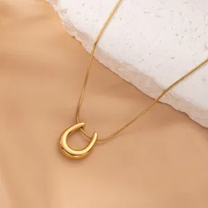 Close-up view of a minimalist 18K gold-plated U-shaped pendant on a sleek snake chain