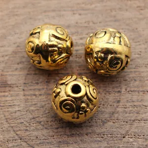 Antique gold metal spacer beads featuring carved vortex relief texture 10mm round beads
