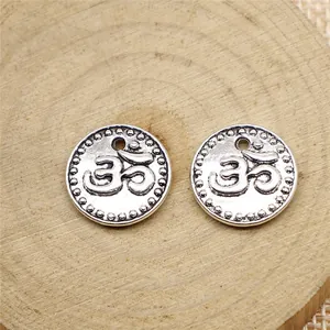 15mm silver-tone Om symbol charms for DIY jewelry making displayed on a wooden surface.