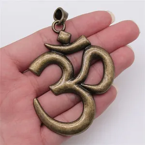 Grande pendente simbolo Om yoga in bronzo vintage tenuto in mano per scala reale