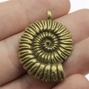 Pendentif spirale ammonite en bronze antique 36x27mm présenté dans la main pour l'échelle
