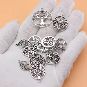 Antiksilberner Lebensbaum Anhänger Set in behandschuhter Hand für Schmuck DIY.
