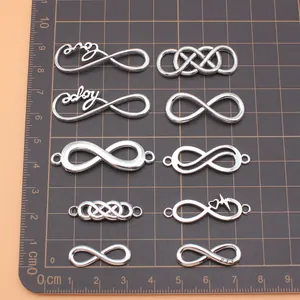 Set of 10 antique silver infinity charms with different designs on a scale mat
