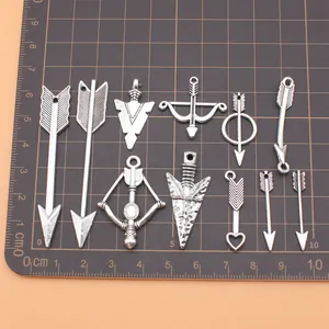 Set of 11 antique silver arrow and bow charms for jewelry making on a centimeter grid