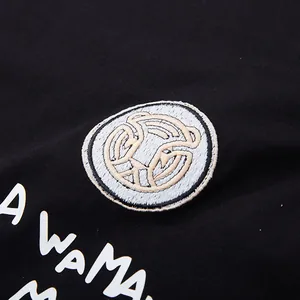 Primo piano di t-shirt in cotone nero con toppa ricamata tonda e scritta bianca