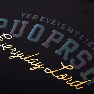 Close-up of black oversized T-shirt with iridescent and gold fashion graphic lettering.