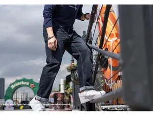 Men's black straight-leg jeans styled with a casual streetwear outfit and white sneakers