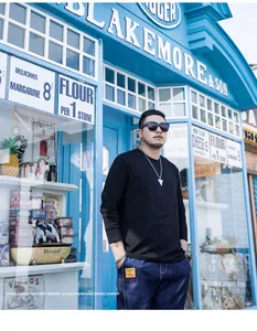 Model wearing a black plus size long-sleeved crewneck T-shirt in urban setting