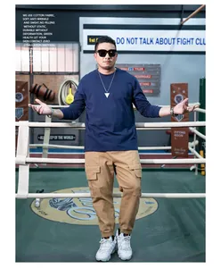 Casual men's navy blue long sleeve crew neck T-shirt paired with khaki cargo pants in gym