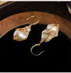Primer plano de pendientes de perlas barrocas hechas a mano con alambre dorado