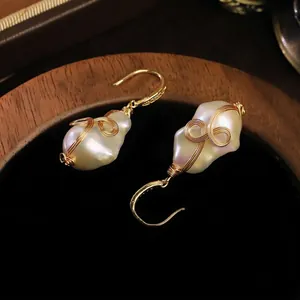 Elegantes pendientes de perlas barrocas con un diseño único de hilo de oro tejido a mano