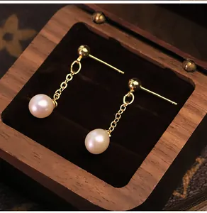 Dettaglio di orecchini di perle d'acqua dolce naturali in una scatola di gioielli in legno