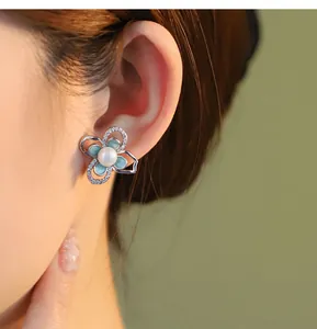 Primo piano di un orecchino a fiore in argento s925 con perla indossato sull'orecchio.