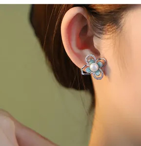 Dettaglio ravvicinato di un orecchino a fiore in argento S925 con perla sull'orecchio
