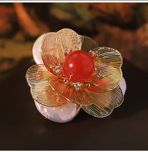 Detailed macro view of a vintage floral brooch with baroque pearls and a red gemstone.