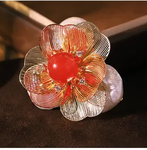 Close-up of elegant flower brooch featuring a red stone and Baroque pearl details