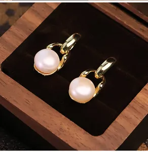 Macro di orecchini a catena d'oro con perle naturali in una scatola regalo di legno