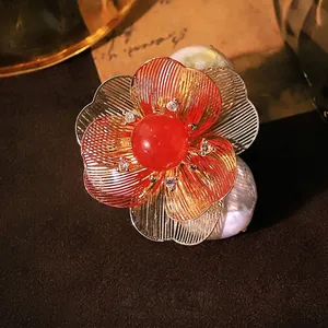 Elegant floral brooch with red stone and Baroque pearls in a vintage gold finish.