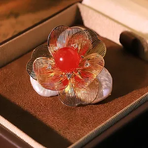 Elegant flower brooch featuring baroque pearls and a red natural stone centerpiece