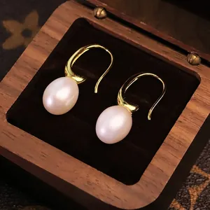 Eleganti orecchini con perle naturali d'acqua dolce e ganci dorati in una scatola di legno