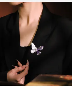 Detailed view of a butterfly brooch with purple zircons and shell on a black blazer.