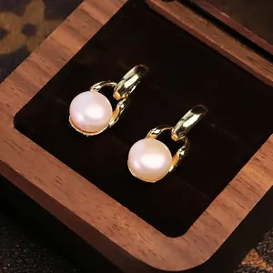 Eleganti orecchini a catena dorati con perle naturali in una scatola regalo di legno
