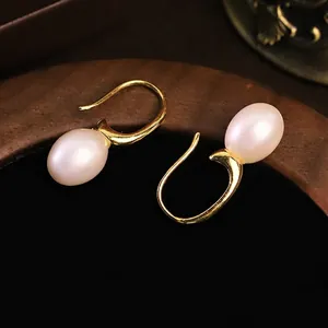 Eleganti orecchini a gancio in oro con perle d'acqua dolce naturali su fondo scuro