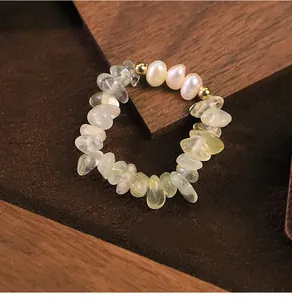 Macro detail of a natural pearl and green prehnite crystal beaded stretch ring on wood