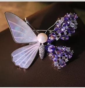 Macro detail of a butterfly brooch with purple zircons and iridescent shell wings.