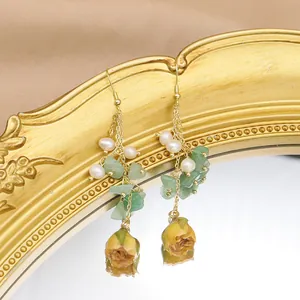 Macro close-up of elegant long dangle earrings with pearls and yellow rose charms