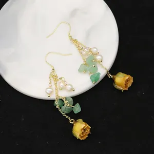 Detailed macro view of long tassel earrings with freshwater pearls and dried rosebuds.