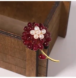 Close-up of elegant flower brooch with red agate petals and fresh water pearl center.