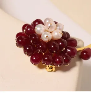 Macro view of handmade brooch with dark red agate petals and freshwater pearl center