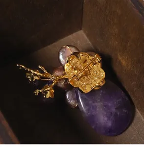 Macro detail showing the reverse side and gold-plated pin of a purple agate pearl brooch