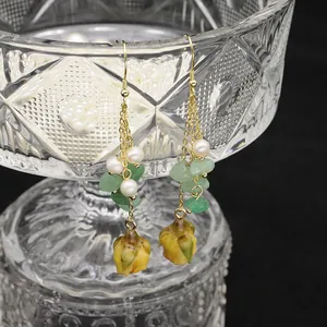 Elegant natural freshwater pearl long drop earrings with green stones and floral buds.