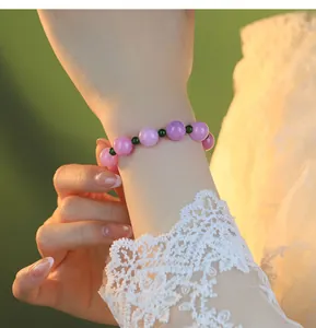 Elegantes Perlenarmband aus Kunzit und grünem Kristall am zarten Handgelenk einer Frau