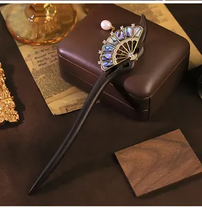 Gros plan d'épingle à cheveux en bois de santal avec perle naturelle et nacre d'abalone.