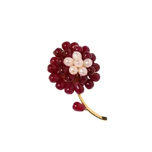 Handmade flower brooch with red agate beads and freshwater pearls on golden stem.
