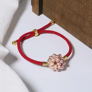 Detailed view of a pink pearl flower ball on a red woven zodiac rope bracelet.