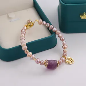 Detail view of natural purple freshwater pearl bracelet with gold Fu charm pendant